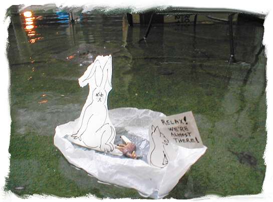 paper rabbit, paper, and plastic gazelle in paper boat with signs saying, relax! We're almost there!