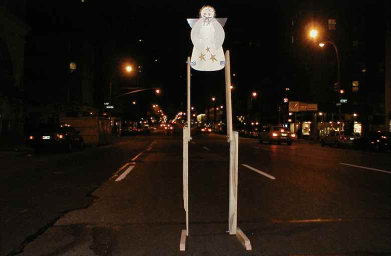 Angel wall hanging on large wooden legs in street